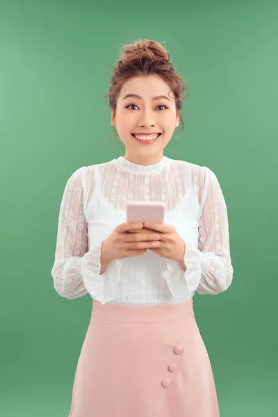 Счастливая Молодая Азиатка Использует Свой Смартфон Стоя Зеленом Фоне — стоковое фото