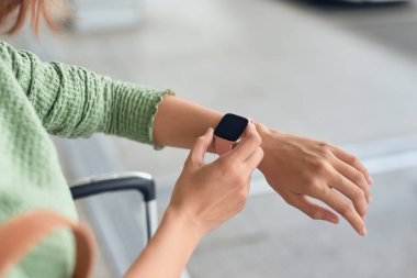 Güzel Asyalı kadın saati kontrol etmek için kol saatine bakar..