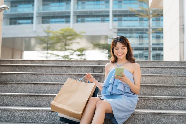 Όμορφη Νεαρή Γυναίκα Τσάντες Ψώνια Χρησιμοποιώντας Τηλέφωνο Και Κάθεται Βήματα — Φωτογραφία Αρχείου