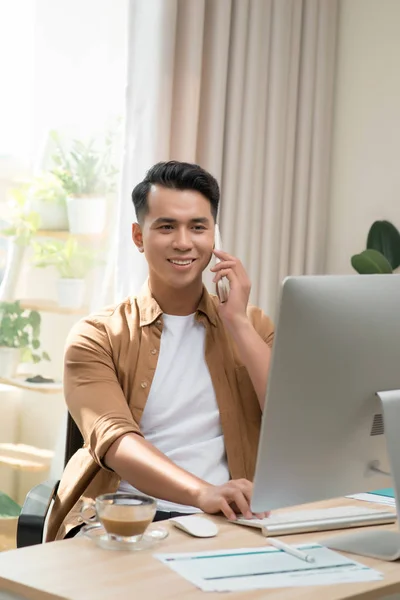 Jovem Empresário Bonito Feliz Usando Computador Falando Telefone Celular Escritório — Fotografia de Stock