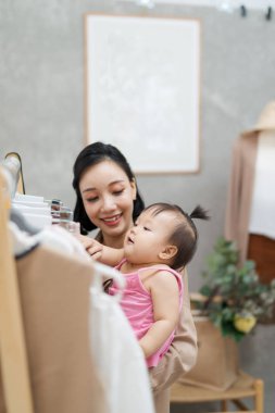 Çalışan bir anne olmak kolay değil! Genç güzel tasarımcı onun bebek kız ile ayakta iken onu atölyesi üzerinde çalışıyor