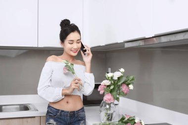 Güzel Asyalı kadın mutfakta çiçek alıyor..