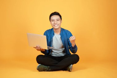 Dizüstü bilgisayar basılı tutup kolunu kadar yükselterek Asya adam başarı ya da başarı kutlamak mutlu heyecanlı.