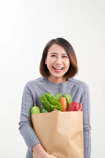 美丽的年轻女子在围裙拿着购物袋充满了新鲜的蔬菜和微笑 — 图库照片