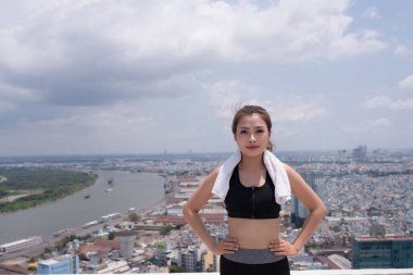 Young asian woman relaxing after exercising on sunny day. Copy space in right side