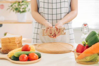 Sağlıklı yiyecekler. Elinde ahşap bir mektup tutan kadın. Aşk, yemek pişirme, maket.