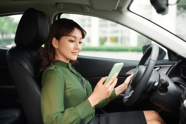 Jovem Mulher Bonita Usando Smartphone Enquanto Dirige Carro — Fotografia de Stock