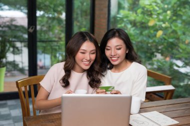 İnternetten internetten alışveriş yapan iki Asyalı genç kadın..