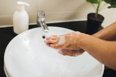 Closeup man's hand washing in bathroom.