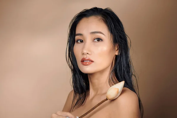 一个年轻美丽的棕褐色皮肤的亚洲女孩 带着米色背景的干荷花芽 — 图库照片