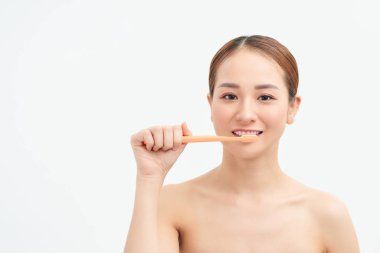 Portrait of woman brushing teeth on light background