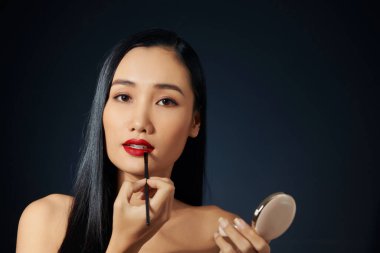 Güzel kadın dudaklarına ruj ile boyar. Güzel bir kadın yüzü. Makyaj ayrıntı. Mükemmel cilt güzellik kız. Kırmızı dudaklar ve tırnaklar manikür