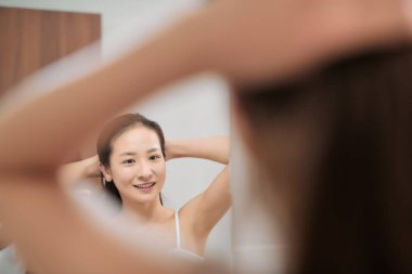 Banyoda saçlarını tarayan, aynaya bakan bir kadın..