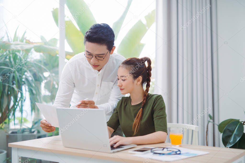 at home, a modern couple preparing their next vacation destination on a laptop, their home is modern and bright