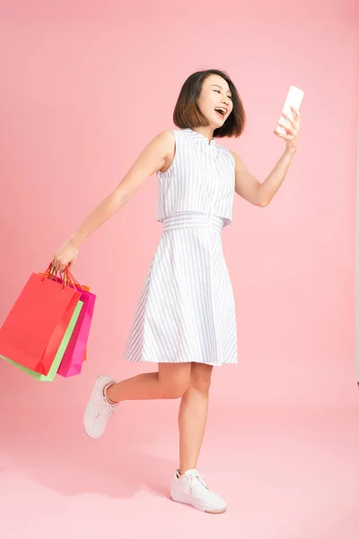 Güzel Kız Alışveriş Torbalarını Tutuyor Akıllı Bir Telefon Kullanıyor Alışveriş — Stok fotoğraf