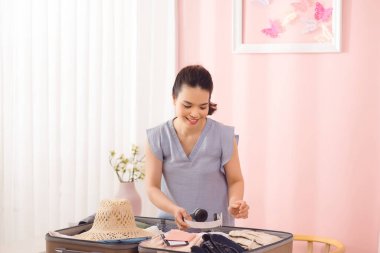 Genç kadın onu çanta ve kıyafet ile seyahat için hazırlanıyor