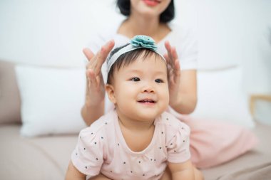 Evde yatakta oturan küçük bir kız. Genç bir anne saç kızı sarılmak