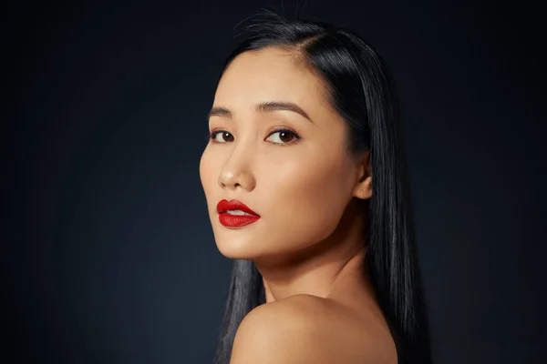 Asian female model with red make up against black background.