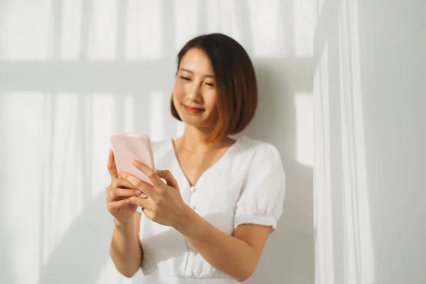 Pretty young lady looking at camera and standing at  wall