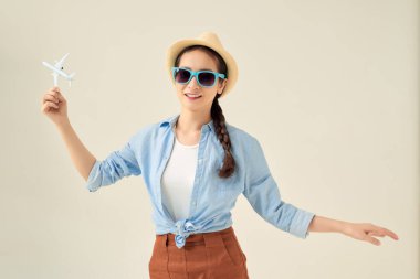Güzel Asyalı kadın elleri uçak modelini tutuyor ve seyahat aksesuarlarıyla tatil planlıyor.