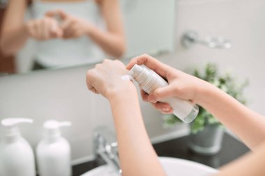 Cildine bakan ve evde banyo yaptıktan sonra nemlendirici ve besleyici el kremi kullanan bir kadın. Cilt bakım ürünü