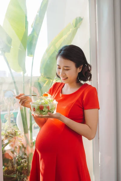 Feliz Joven Embarazada Comiendo Ensalada Verduras Sonriendo Cerca Ventana Casa — Foto de Stock
