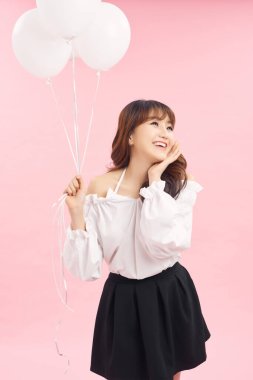 Asyalı portresi pembe hava balonlarıyla ayakta duruyor, ellerini kaldırıyor. Mutlu