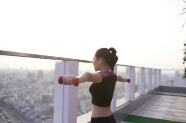 Kararlı kadın evde kilo kaybediyor ve halterlerle egzersiz yapıyor.