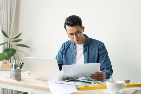 Ofis masasında çalışan yakışıklı bir erkek mimar.