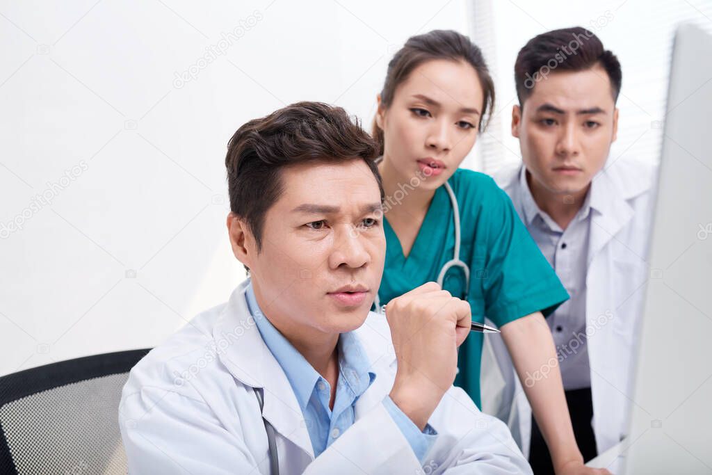 Team of doctors working and having on laptop in medical office 