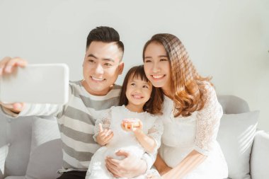 Aile evdeki kanepede otururken selfie çekiyor.