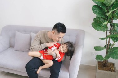 Baba ve kızı kanepede otururken birbirlerine sarılıyorlar.