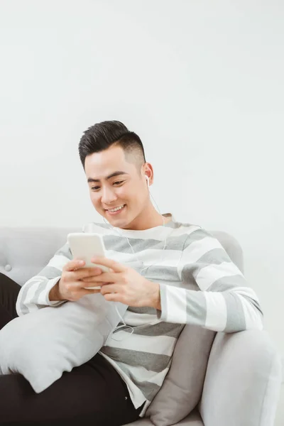 Jovem Sorridente Feliz Usando Dispositivo Smartphone Moderno Enquanto Sentado Sofá — Fotografia de Stock