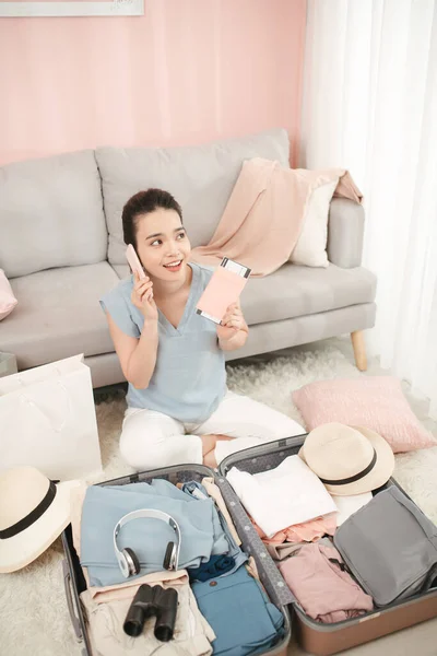 Tourist talking on phone, booking hotel and holding passport, ticket, preparing for vacation