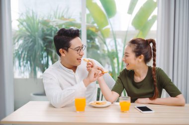 Genç çift kahvaltı ederken birbirlerini besliyorlar.