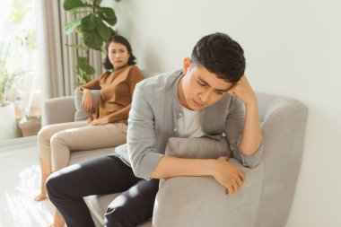 Üzgün kadın kanepede erkeğin yanında oturuyor.