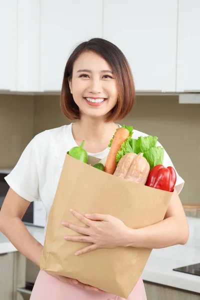 年轻的亚洲女人拿着购物袋 厨房里有蔬菜 — 图库照片