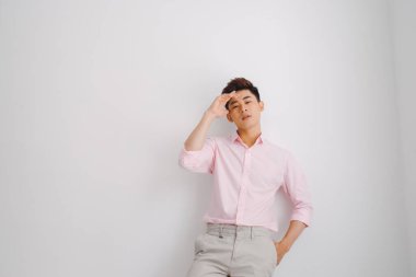 Beyaz arka planda duran pembe gömlekli genç Asyalı adam.