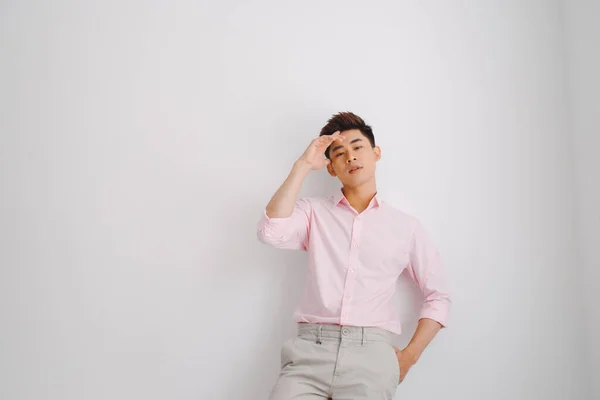 身穿粉色衬衫站在白色背景之上的亚洲年轻人 — 图库照片