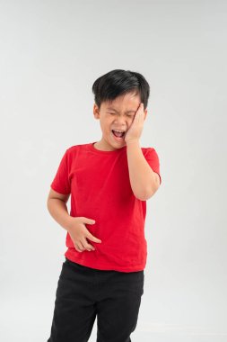 Karnı ağrıyan üzgün küçük Asyalı çocuk, karnını tutuyor, beyaz arka planda soyutlanmış..