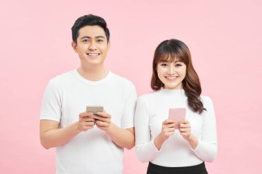 Asyalı kadın ve erkeğin renkli arka planda izole edilmiş akıllı telefonları kullanması