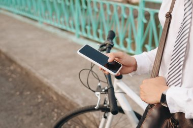 Bir erkeğin şehirde elektrikli bisiklet sürerken akıllı telefonunda kendini izleme uygulaması kullanırken yakın plan fotoğrafı.