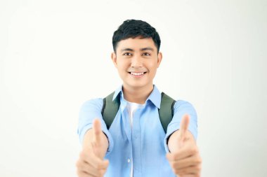 Sırt çantalı genç bir öğrenci beyaz arka planda baş parmak hareketleriyle iki elini tutuyor.