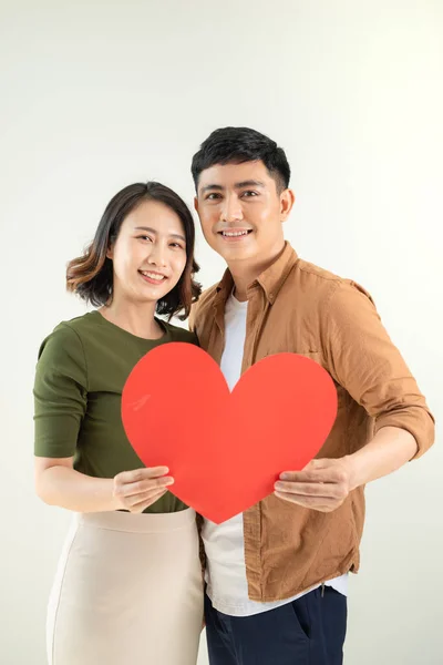 Happy young Asian couple holding heart shape over white background.