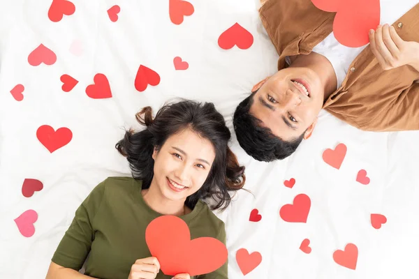 Self portrait of sweet cute couple lying head to head on the floor with small red hearts