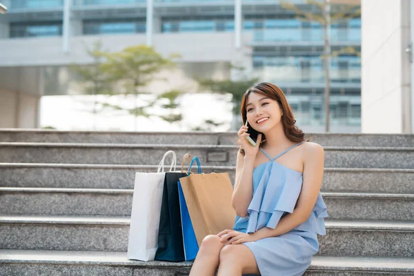 Šťastná Mladá Asijská Žena Nákupními Taškami Volá Mobilní Telefon Sedí — Stock fotografie