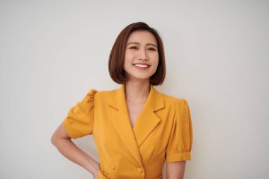 Güzel genç kadın beyaz duvara yaslanıyor.