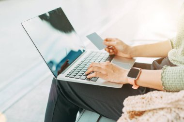 Havaalanında laptopuyla ödeme yapmak için kredi kartı kullanan genç bir kadın..