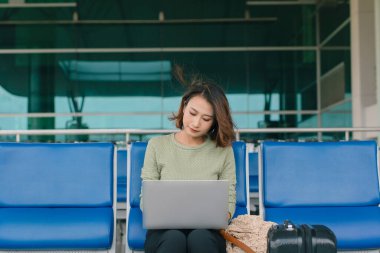 Kahve zamanı. Havaalanı salonunda oturan, kahve içen ve dizüstü bilgisayarla çalışan çekici bir kadın.