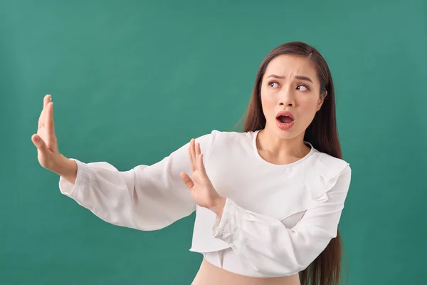 Young woman afraid and terrified with fear expression stop gesture with hands, shouting in shock.